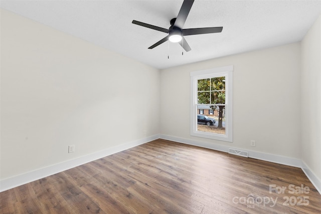 unfurnished room with visible vents, ceiling fan, baseboards, and wood finished floors