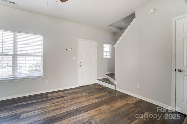 foyer entrance with a ceiling fan, visible vents, baseboards, and dark wood-style flooring