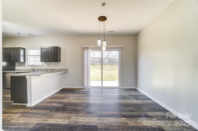 kitchen featuring light countertops, dark wood-style flooring, a peninsula, and baseboards