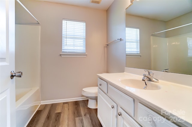 bathroom featuring baseboards, toilet, vanity, wood finished floors, and shower / bathtub combination