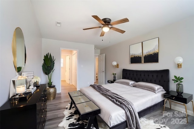 bedroom featuring a ceiling fan, visible vents, wood finished floors, and ensuite bathroom