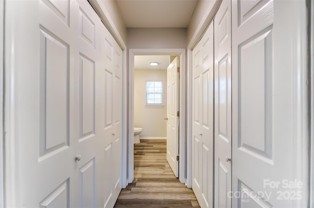 hall featuring wood finished floors and baseboards