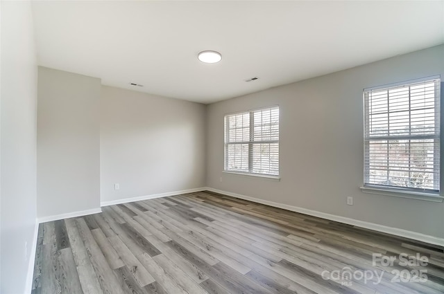 spare room with visible vents, baseboards, and wood finished floors