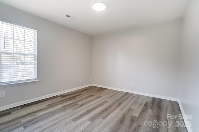 unfurnished room with wood finished floors, a wealth of natural light, and baseboards