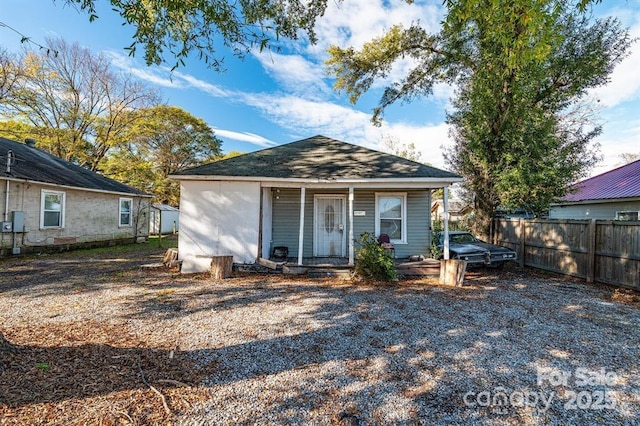 bungalow-style home with covered porch, an outbuilding, and fence