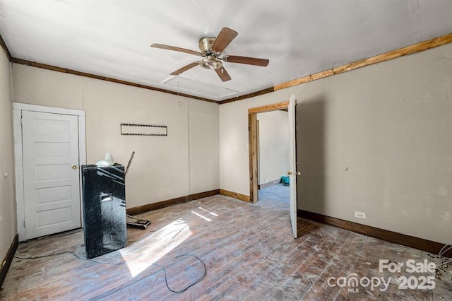 empty room with attic access, ceiling fan, and baseboards