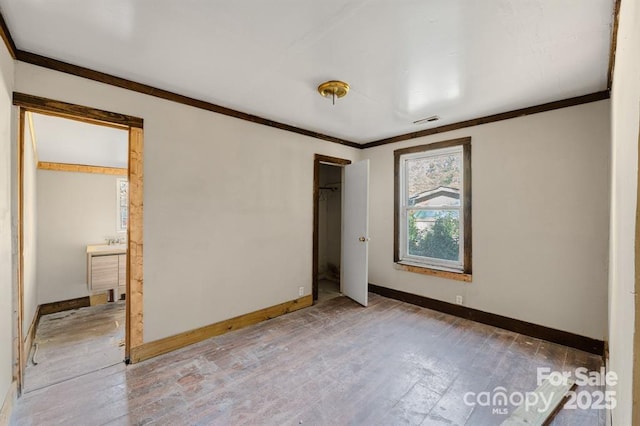 unfurnished bedroom featuring ornamental molding, wood finished floors, visible vents, and baseboards