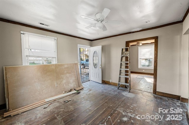 empty room featuring hardwood / wood-style flooring, baseboards, visible vents, and crown molding