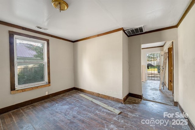 unfurnished room featuring baseboards, visible vents, hardwood / wood-style floors, and ornamental molding