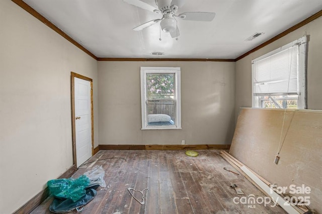 unfurnished room featuring baseboards, wood-type flooring, visible vents, and crown molding