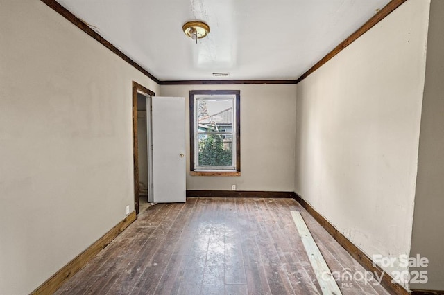 unfurnished room featuring baseboards, crown molding, visible vents, and hardwood / wood-style floors