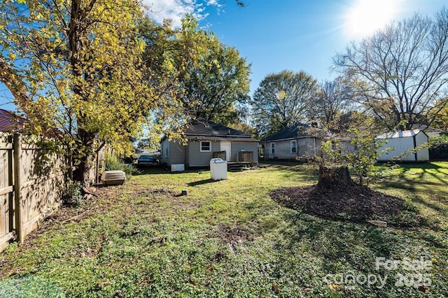 view of yard with an outbuilding, fence, and a storage shed