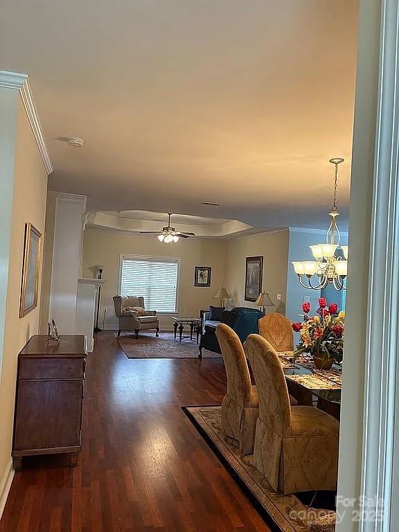 dining area with ceiling fan with notable chandelier, wood finished floors, and crown molding