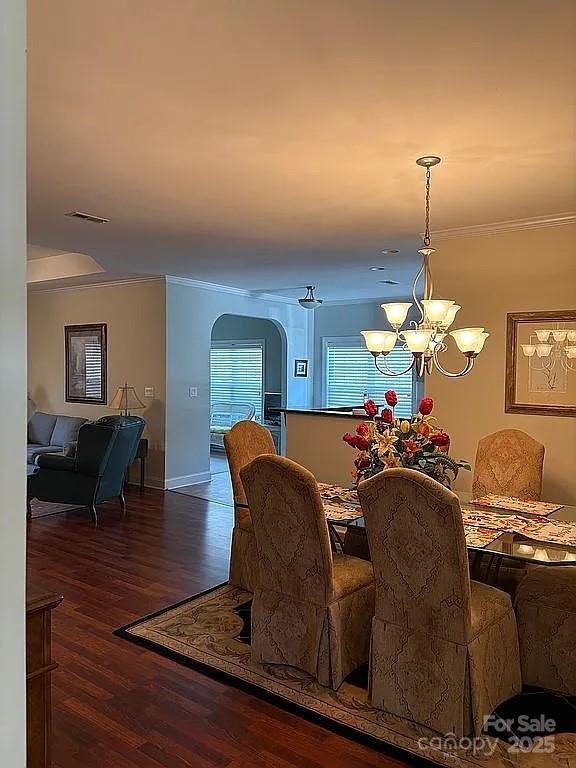 dining space featuring visible vents, a chandelier, wood finished floors, and ornamental molding