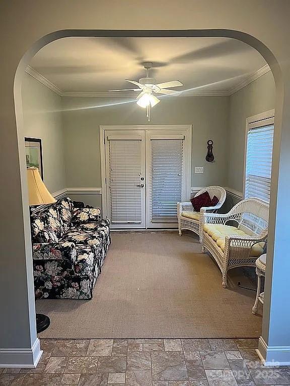 bedroom featuring arched walkways, baseboards, a ceiling fan, and crown molding