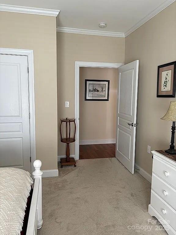 bedroom with baseboards, light colored carpet, and crown molding