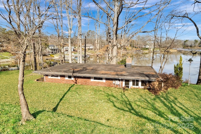 exterior space featuring a water view, a chimney, and a yard