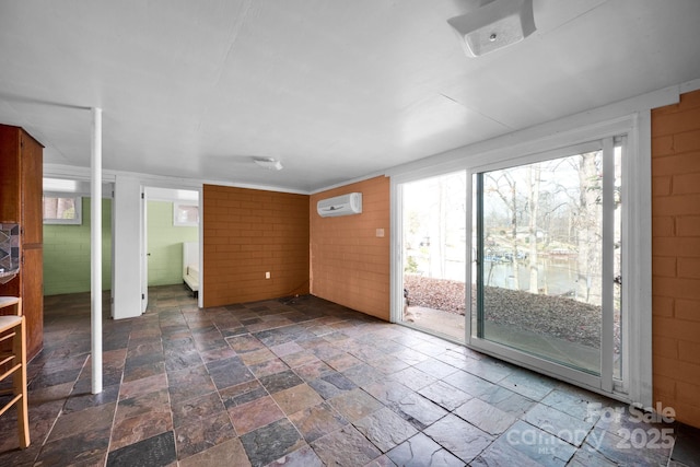 empty room featuring plenty of natural light, stone finish flooring, and a wall mounted AC