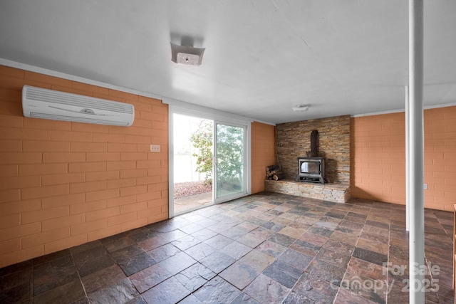 unfurnished living room with a wall mounted AC, stone tile flooring, and a wood stove