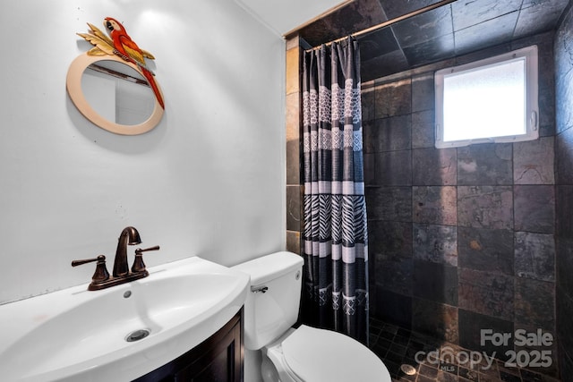 bathroom featuring tiled shower, vanity, and toilet