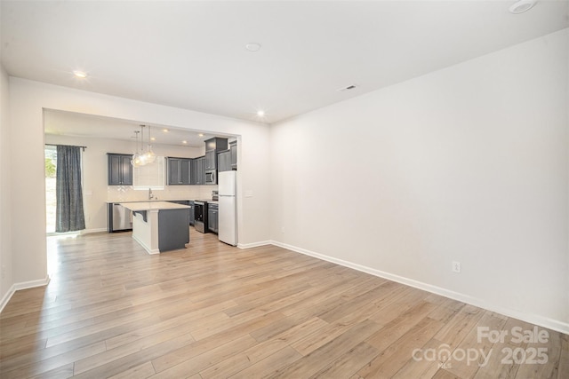 5532 Axil Ln, Charlotte, NC 28269 - interior space featuring light wood-style floors, a kitchen island, appliances with stainless steel finishes, and light countertops