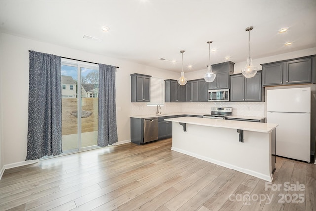 5532 Axil Ln, Charlotte, NC 28269 - kitchen featuring stainless steel appliances, a sink, a kitchen breakfast bar, light wood-style floors, and light countertops