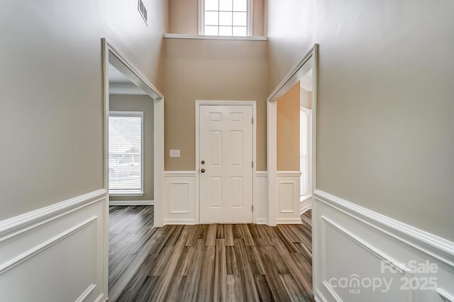 entryway featuring a wainscoted wall, a healthy amount of sunlight, and dark wood-style flooring