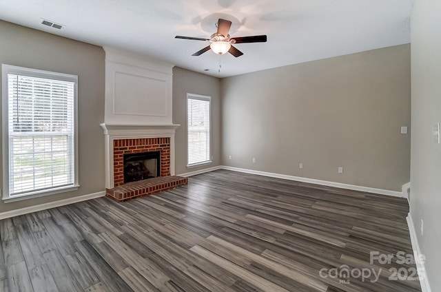 unfurnished living room featuring visible vents, a brick fireplace, dark wood-type flooring, and baseboards