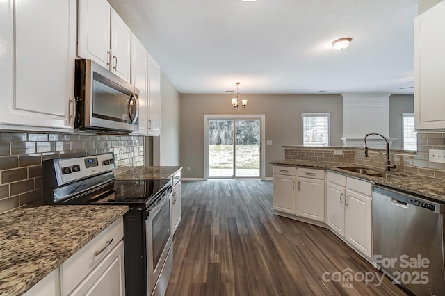 kitchen with backsplash, stainless steel appliances, dark wood-style floors, white cabinetry, and a sink