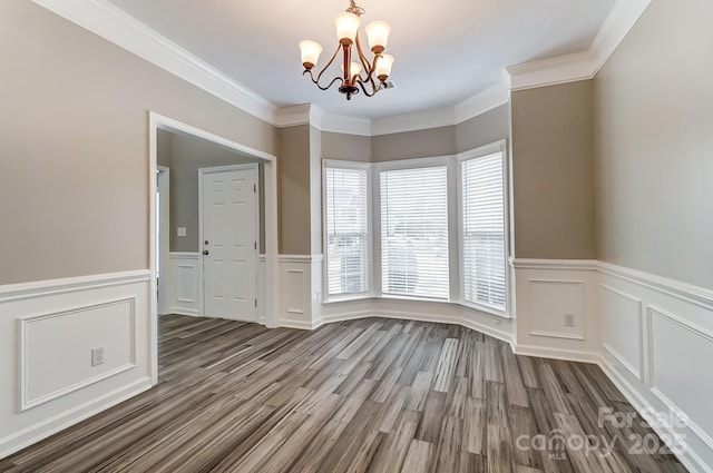 unfurnished room with a wainscoted wall, wood finished floors, a chandelier, and crown molding