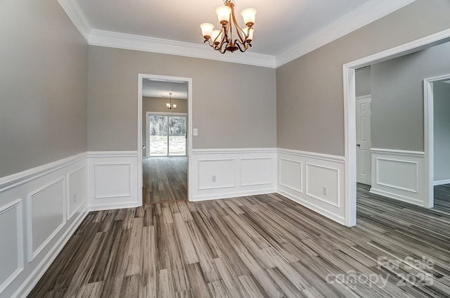 empty room featuring a chandelier, ornamental molding, and wood finished floors