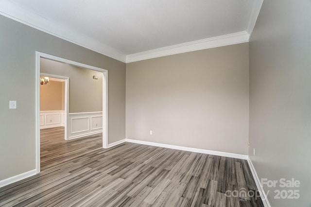 unfurnished room with baseboards, wood finished floors, crown molding, and a decorative wall