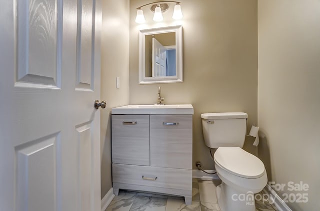 bathroom featuring baseboards, toilet, marble finish floor, and vanity