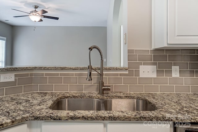 kitchen featuring white cabinetry, light stone countertops, tasteful backsplash, and a sink