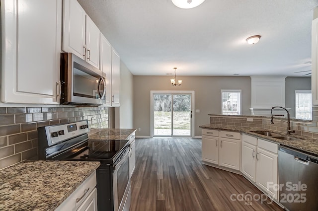 kitchen with a sink, a wealth of natural light, stainless steel appliances, white cabinetry, and dark wood-style flooring