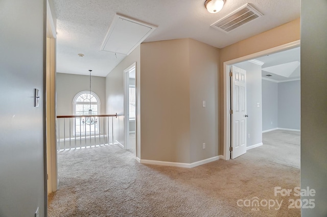 corridor featuring visible vents, carpet, attic access, and a textured ceiling