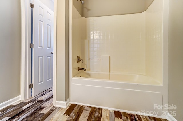 bathroom featuring wood finished floors, baseboards, and shower / bath combination