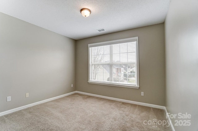 empty room featuring visible vents, baseboards, a textured ceiling, and carpet flooring