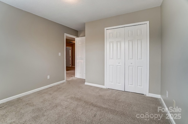 unfurnished bedroom with carpet, baseboards, and a closet