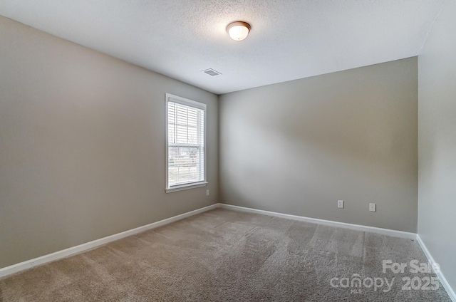 empty room with baseboards, visible vents, carpet floors, and a textured ceiling