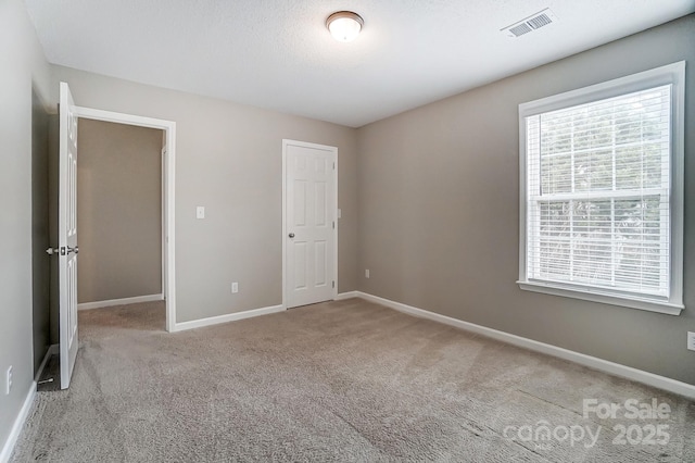 unfurnished bedroom featuring baseboards, carpet floors, and visible vents