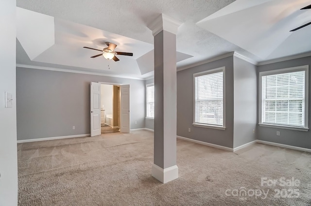 carpeted empty room with ceiling fan, a tray ceiling, baseboards, and ornamental molding