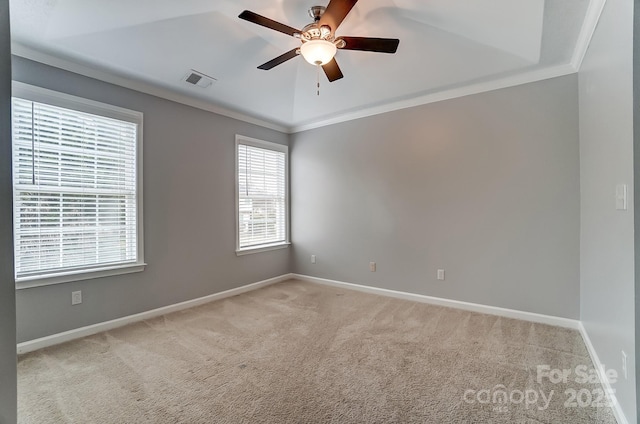 carpeted spare room featuring ceiling fan, baseboards, visible vents, and ornamental molding