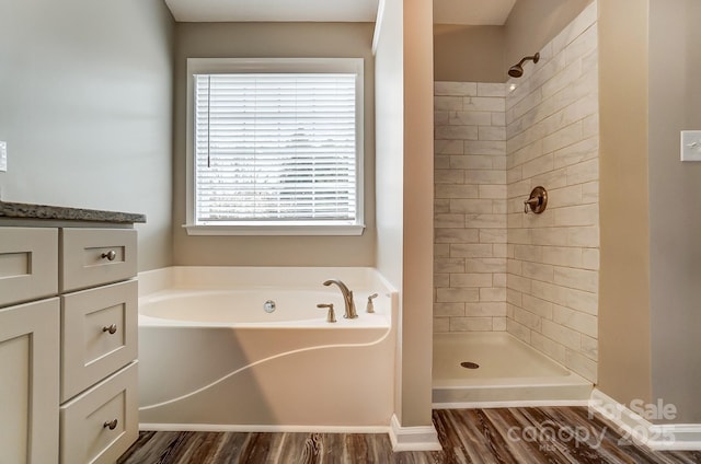 full bathroom featuring a bath, tiled shower, vanity, and wood finished floors