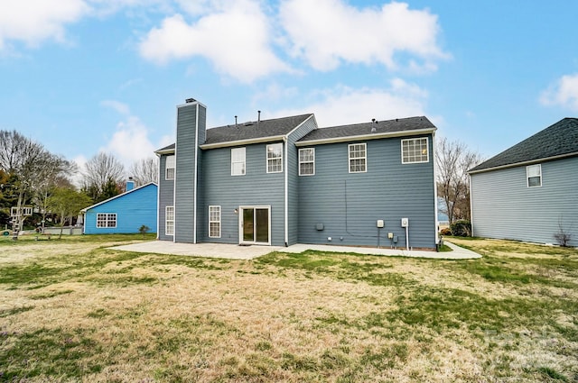 rear view of property featuring a yard, a chimney, and a patio