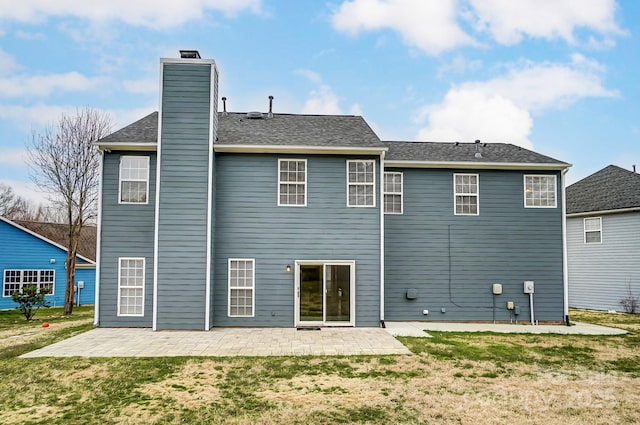 back of property featuring a patio, a yard, roof with shingles, and a chimney