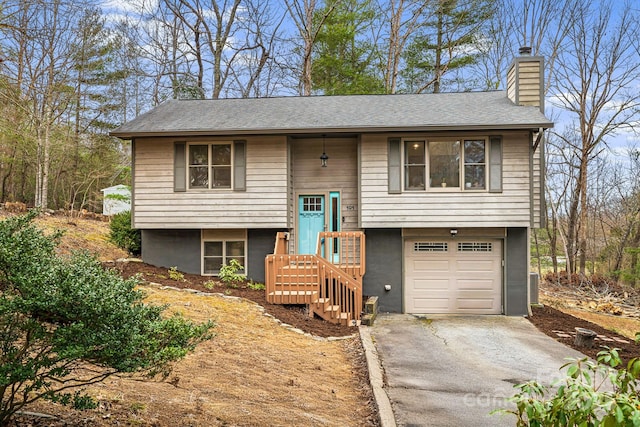 split foyer home featuring driveway, an attached garage, a chimney, and central AC unit