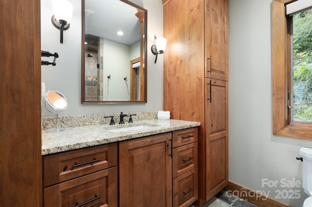 bathroom featuring vanity, toilet, baseboards, and plenty of natural light