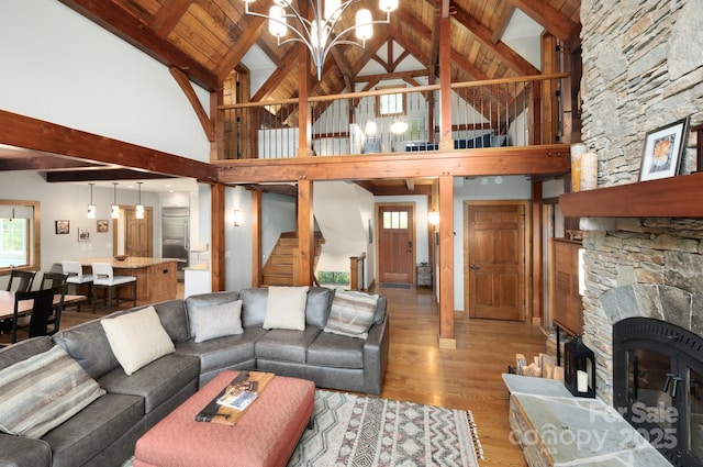 living area with stairway, light wood finished floors, lofted ceiling with beams, wood ceiling, and a chandelier