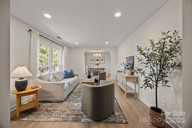 living room with baseboards, visible vents, arched walkways, wood finished floors, and recessed lighting